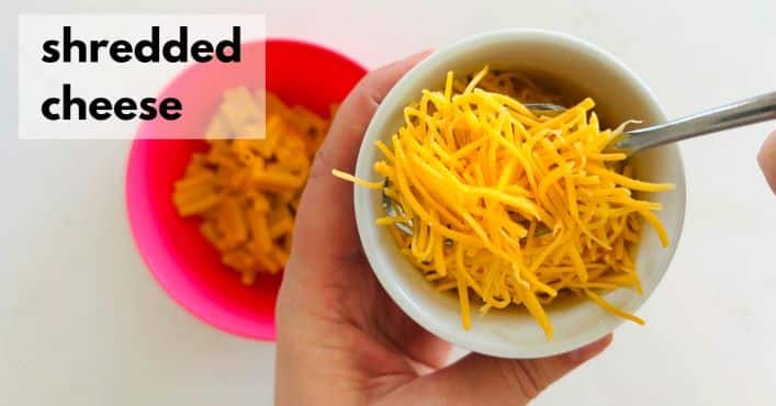 adding shredded cheese to mac n cheese